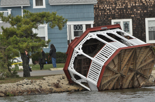 Gazebo resting on its side against the shore with its base visible.