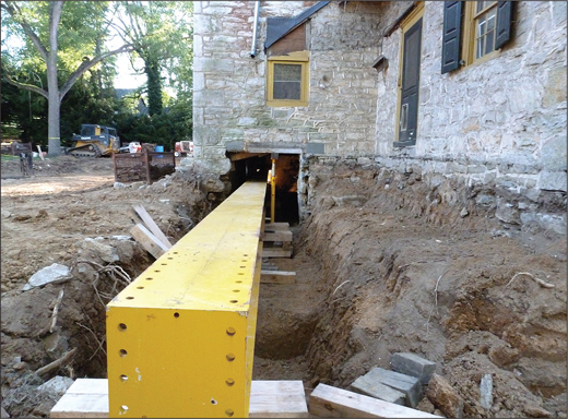 A stone house with a yellow beam inserted through the foundation.