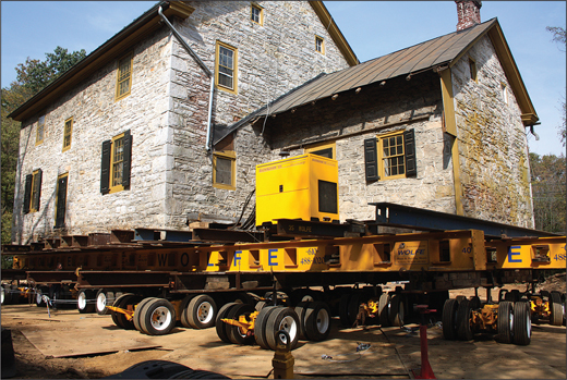 A stone house being lifted onto a trailer.