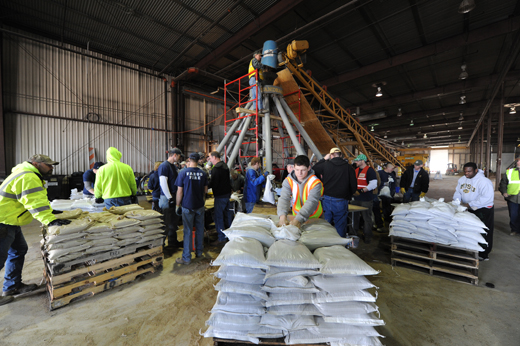 Pallets of sandbags in a warehouse with workers making sure they are ready to go.