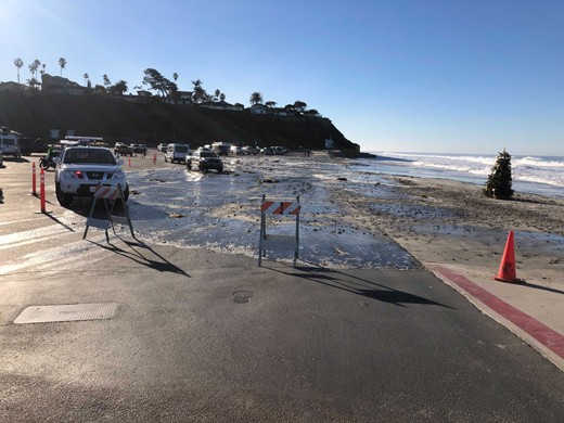 Flooded parking lot with the flooded area marked off with orange traffic cones and emergency vehicles.