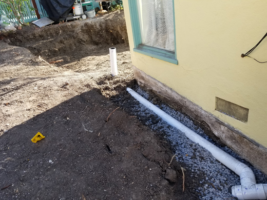 Trench dug around a house with a pipe installed waiting for gravel and topsoil.