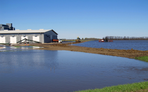 Agricultural building elevated on fill surrounded by water.