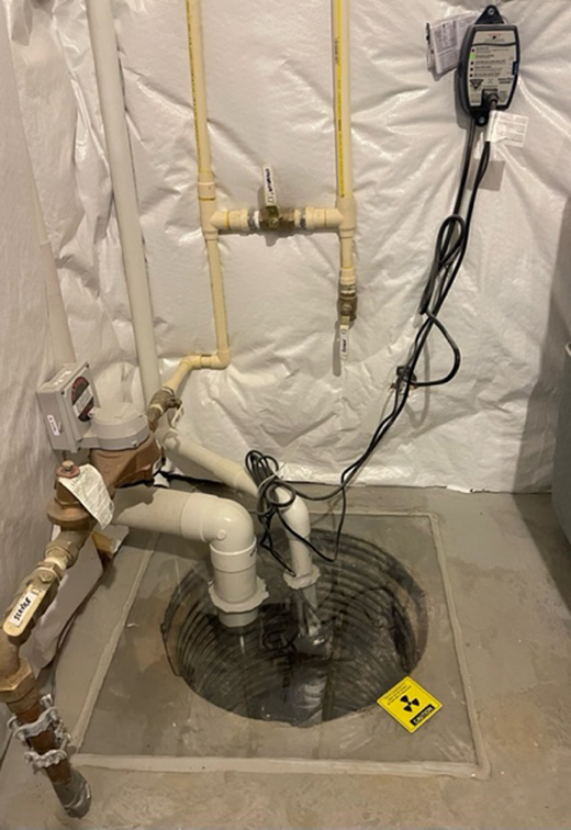 The interior of a sump pump from above, showing connecting pipes.