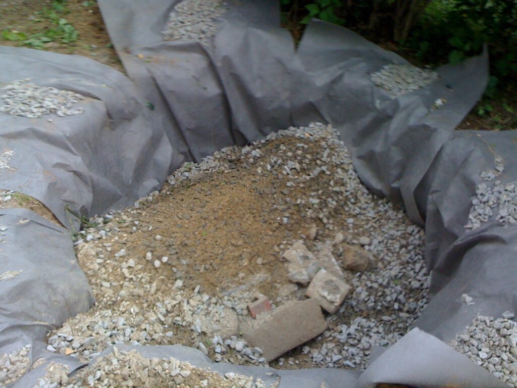 A close up of gravel in a tarp lined drywell hole