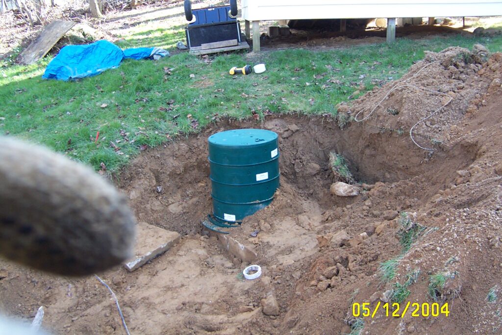 A small green septic tank mid-installation, in the pit but not yet covered.