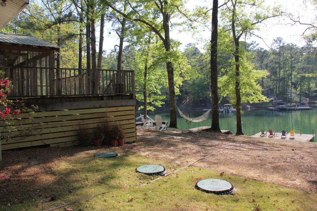 The covers of two septic tanks pictured behind a house and near a recreational lake with docks.