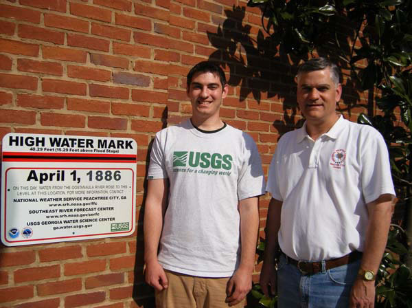 Two men standing by the first high water mark sign in Rome, GA. The sign shares that Rome’s record flood occurred on April 1, 1886, when the Ostanaula River rose to a stage of 40.3 feet, inundating some parts of downtown Rome with more than 20 feet of water.