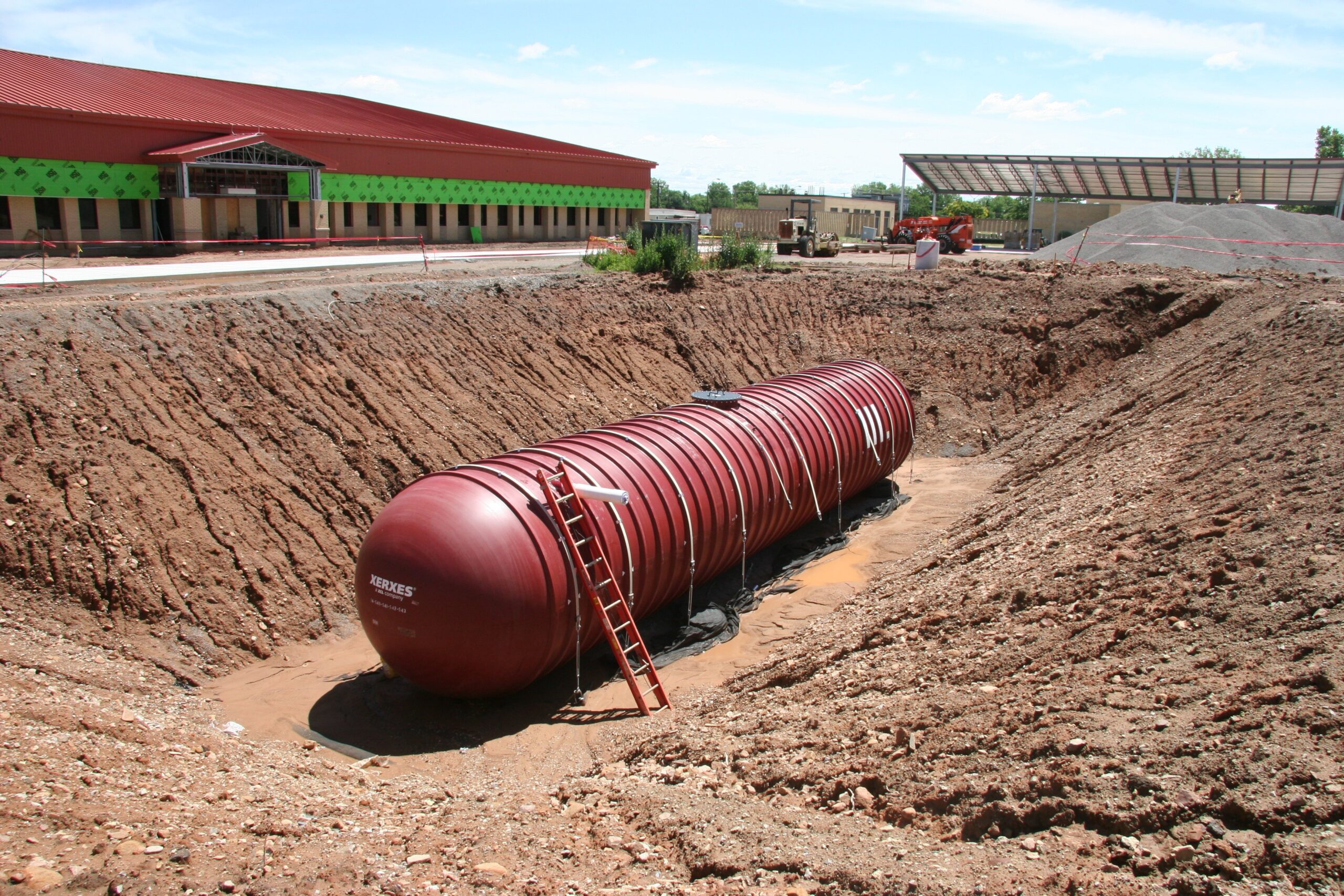 One red tank sitting in the bottom of a pit waiting to be covered